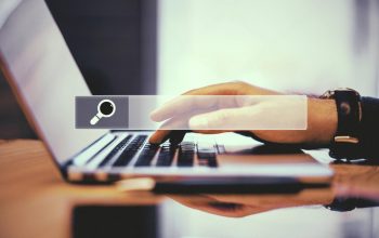 Hand typing on a laptop with a search bar overlay, representing changing a business domain name